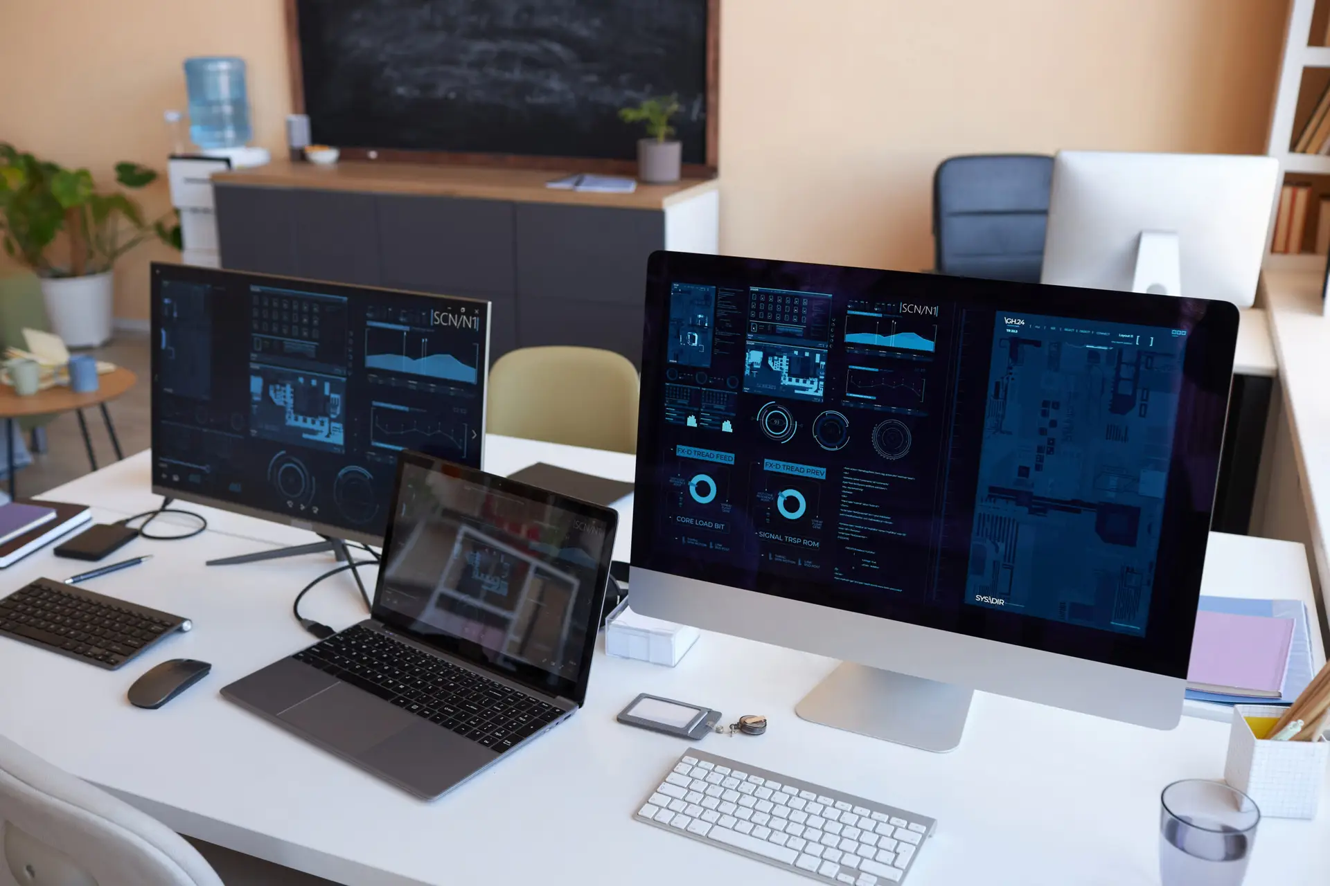 Laptop standing on desk between two computers with graphic data on screens